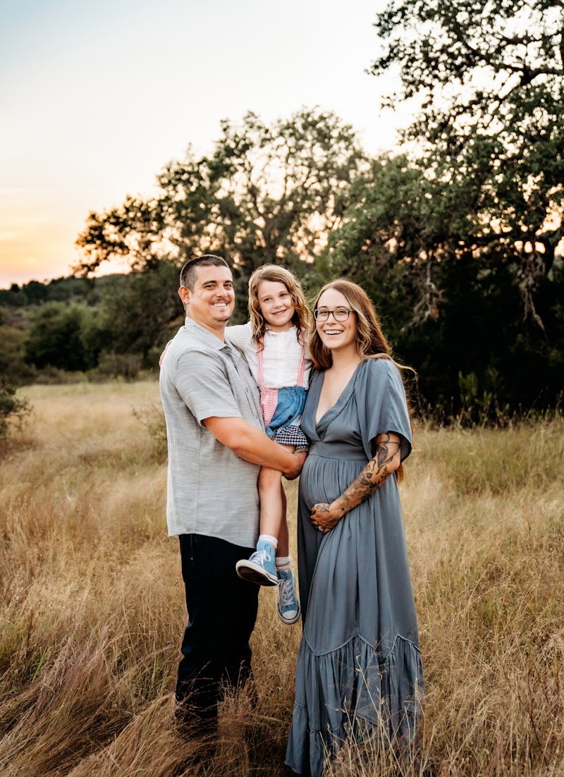A family of three together in a field at golden hour